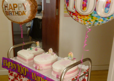 100th birthday cake on a trolley decorate with helium balloons