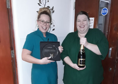 Two Care Staff at Meyer House with their winning trophy and a bottle of Paul Langier Champagne