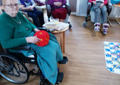 Meyer House Care Home residents seated around a floor snakes and ladders game, with one lady holding a large red dice
