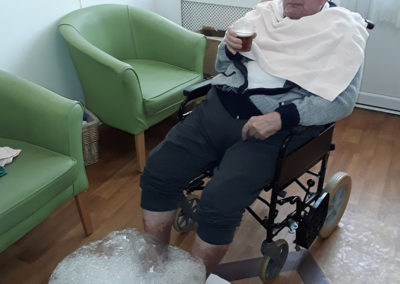 Male resident relaxing in a chair with his feet in a bubbly foot spa