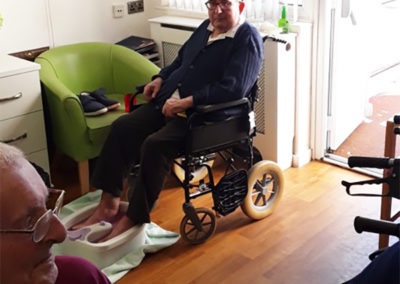 A male resident sitting in a wheelchair enjoying a foot spa