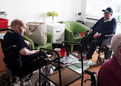 Two male residents sitting in wheelchairs enjoying foot spas