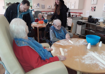 Group of residents sat around a table making sausage rolls together