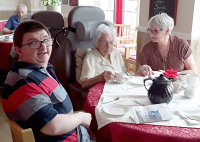 Resident and her family enjoying tea and scones at Meyer House Care Home