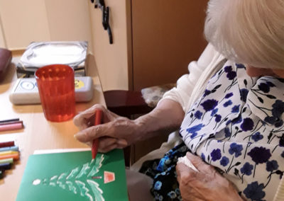 A lady resident making a Christmas card with stencils