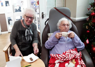 Lady resident and family member enjoying tea and biscuits together