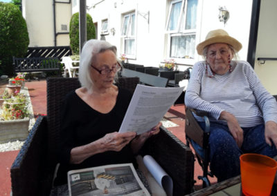Lady residents reading to another outside at Meyer House